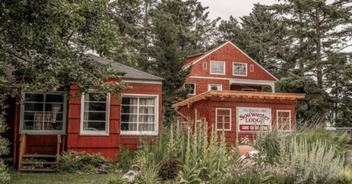 Two red lodges surrounded by greenery, with a sign for "Soul West Lodge" in front of one building.
