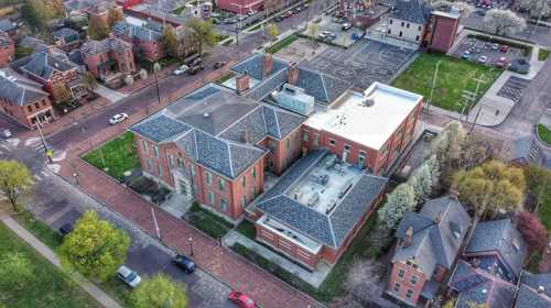 Aerial view of a large brick building surrounded by green spaces and residential areas.