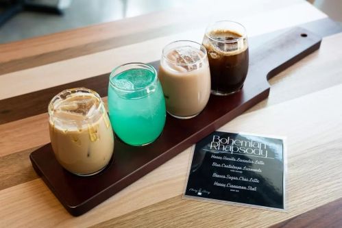 Four colorful drinks in glasses on a wooden tray, alongside a menu titled "Bohemian Rhapsody."