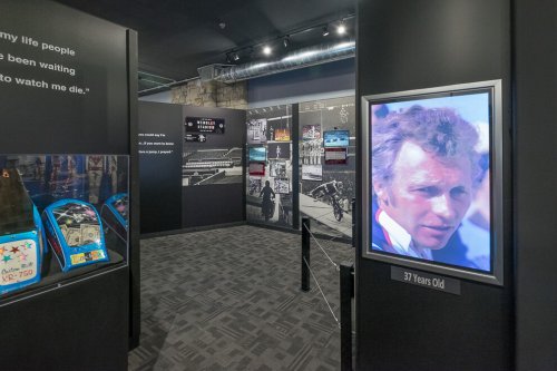 A museum exhibit featuring displays, photographs, and a portrait of a man at 37 years old.
