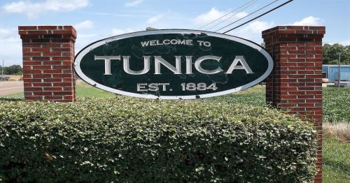 Welcome sign for Tunica, established in 1884, surrounded by greenery and a clear blue sky.