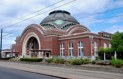 Historic Union Station building with a domed roof, brick facade, and surrounding greenery under a cloudy sky.