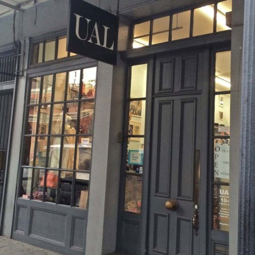 Exterior of a store with large windows and a sign reading "UAL," showcasing a welcoming entrance.