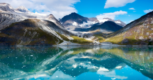 A serene mountain landscape with a turquoise lake reflecting the peaks and blue sky above.
