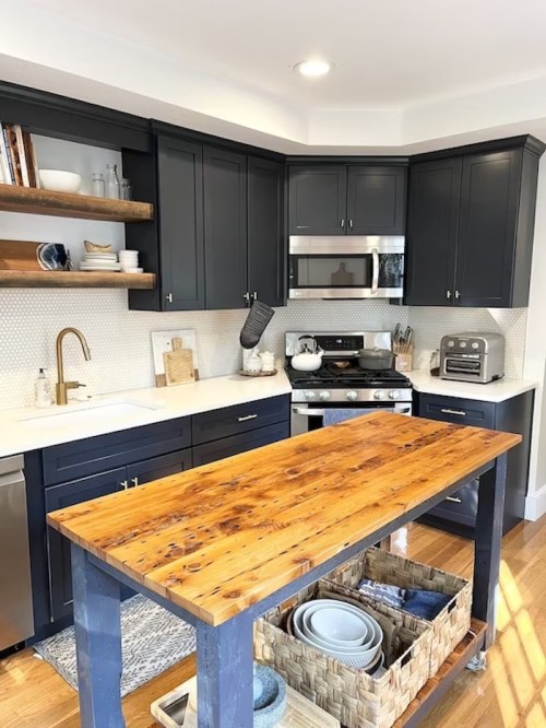 Modern kitchen with dark cabinets, a wooden island, and open shelving displaying dishes and decor.