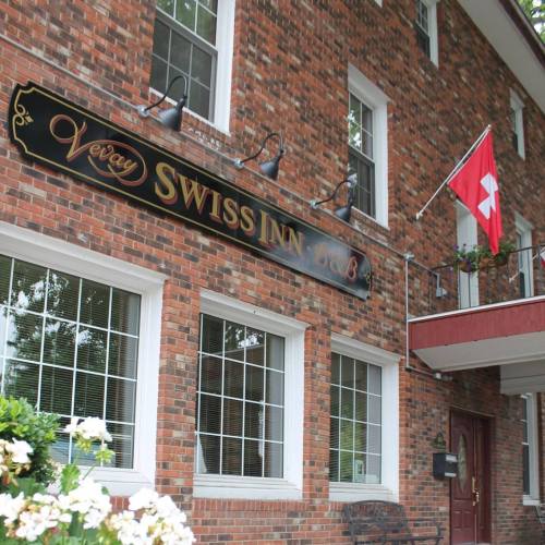 Exterior of the Veray Swiss Inn B&B, featuring a brick facade and a Swiss flag hanging from the balcony.