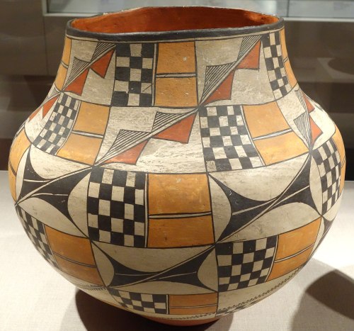 A decorative pottery vase featuring geometric patterns in orange, black, and cream colors.