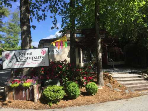 A storefront with a sign reading "Jones Company" surrounded by greenery and colorful decorations, indicating it's open.