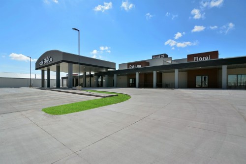 Modern building exterior with signs for a hotel, floral shop, and a restaurant, set against a clear blue sky.