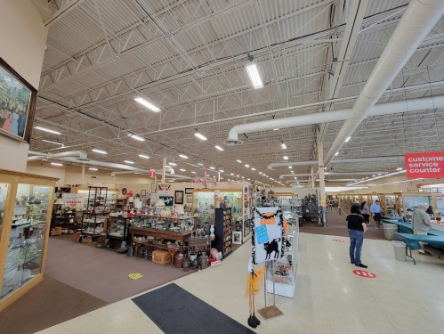 A spacious antique store filled with various collectibles, displays, and shoppers browsing the aisles.