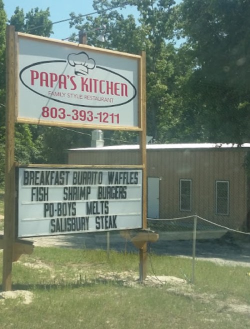 Sign for Papa's Kitchen restaurant featuring menu items like breakfast burrito, waffles, fish, shrimp, and burgers.