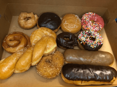 A box of assorted donuts, including glazed, chocolate, and sprinkled varieties.