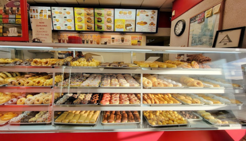 A display case filled with a variety of colorful donuts and pastries in a bakery.