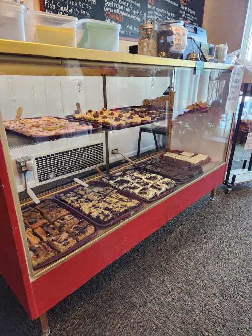 A display case filled with various baked goods, including cookies and bars, in a cozy café setting.