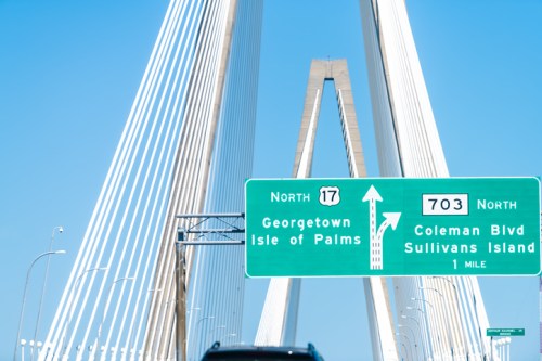 A highway sign directing to Georgetown and Isle of Palms, with a bridge structure in the background against a blue sky.