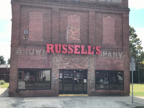 Exterior of a brick building with "RUSSELL'S" prominently displayed above the entrance, featuring a weathered facade.
