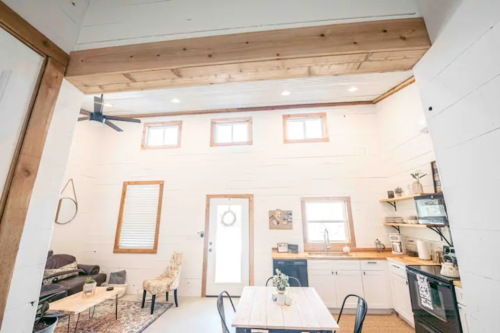 Bright, modern interior of a cozy cabin with a dining area, kitchen, and living space featuring wooden accents.