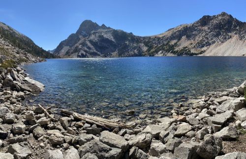 A serene mountain lake surrounded by rocky shores and towering peaks under a clear blue sky.