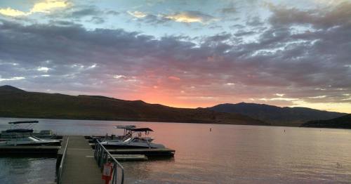 Sunset over a calm lake with boats docked and mountains in the background, creating a serene atmosphere.