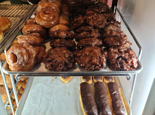 A display of assorted pastries, including glazed donuts, chocolate-covered treats, and apple fritters.