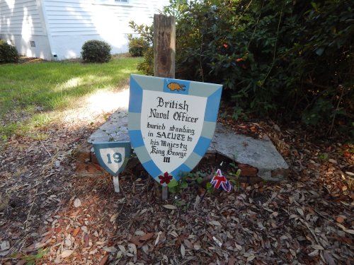 A decorative sign honoring a British naval officer, with a shield design and a small Union Jack flag nearby.