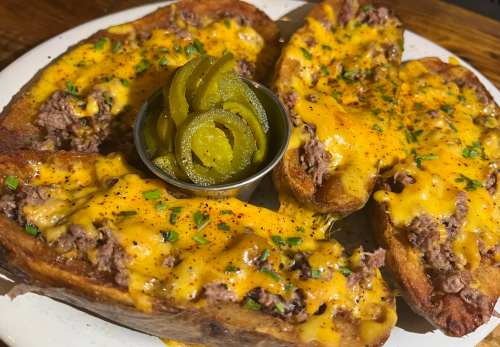 A plate of cheesy beef-stuffed bread topped with jalapeños and garnished with chives.