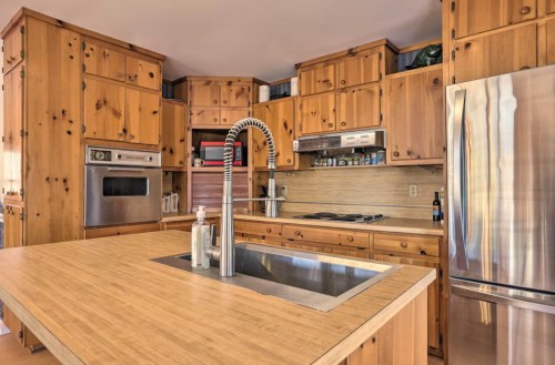A wooden kitchen with cabinets, stainless steel appliances, and a large island with a sink. Bright and spacious design.