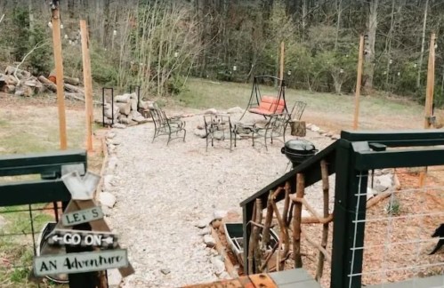 A cozy outdoor gathering area with a fire pit, chairs, and a sign that says "Let's Go On An Adventure."