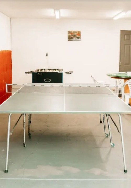 A spacious room with a ping pong table in the foreground and a foosball table in the background.