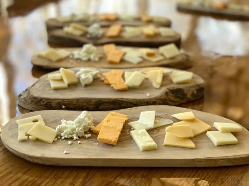 A wooden platter with various cheese slices arranged artistically on a table.