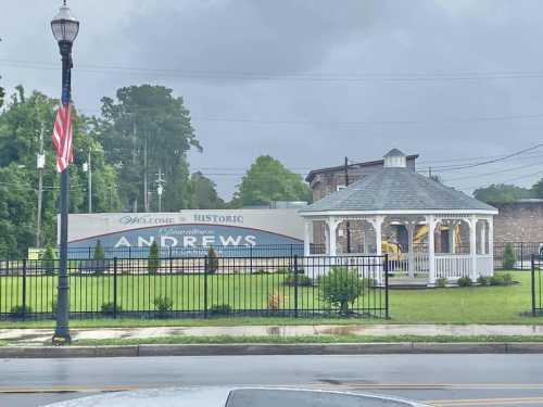 A gazebo in a park with a "Welcome to Historic Andrews" sign in the background, under a cloudy sky.