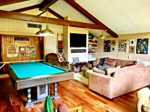 Cozy living space featuring a pool table, comfortable seating, and decorative wall art in a warm, inviting atmosphere.