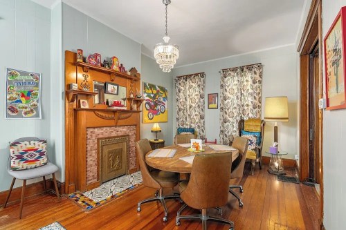 Cozy dining room with a round table, vintage decor, a chandelier, and colorful curtains against wooden floors.