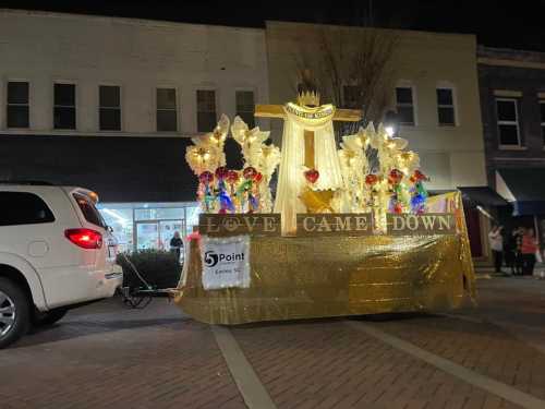 A decorated parade float with lights and colorful decorations, parked on a street at night.