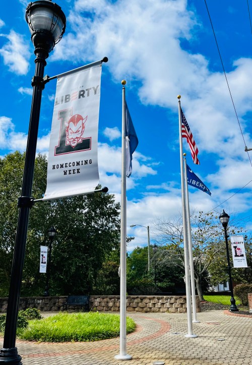 Banners for Homecoming Week at Liberty, featuring a mascot, flags, and a blue sky with clouds.