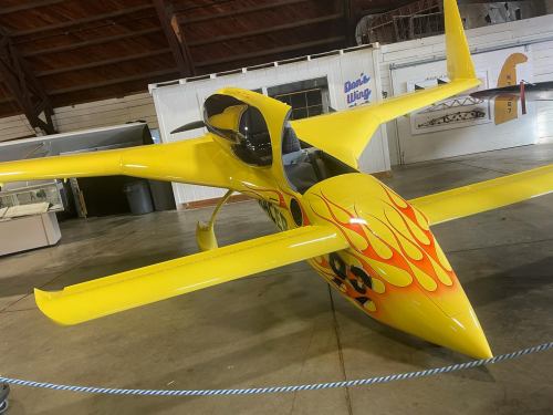 A bright yellow aircraft with flame designs, displayed indoors in a hangar.