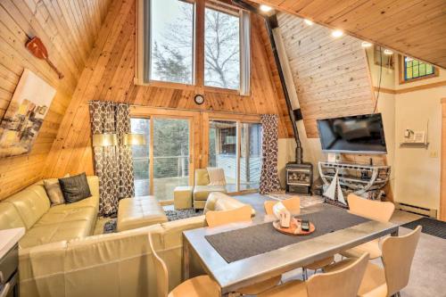 Cozy A-frame cabin interior with wooden walls, large windows, modern furniture, and a dining area.