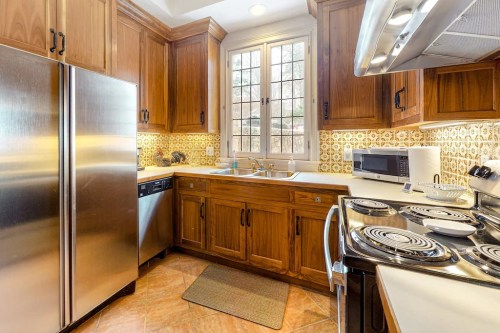 Cozy kitchen with wooden cabinets, stainless steel appliances, and a window above the sink, featuring patterned backsplash.