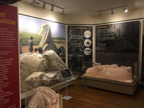 Exhibit showcasing historical artifacts and information about the Dunes and film history, featuring a large sphinx sculpture.