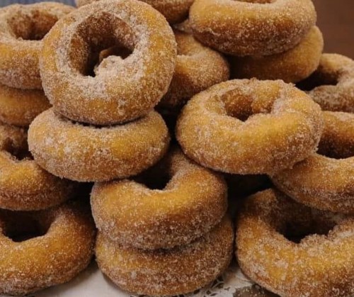 A stack of freshly made, sugar-coated donuts arranged in a tempting pile.