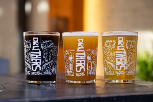 Three glasses of craft beer on a table, featuring unique designs from Druthers Brewing Company.