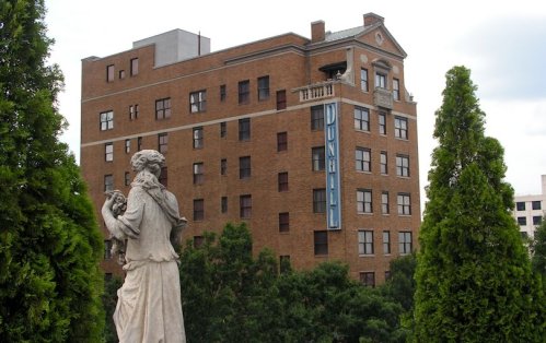 A statue in the foreground with a brick building in the background featuring a sign that reads "Dunhill."