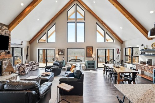 Spacious modern living room with high ceilings, large windows, and a mix of seating and dining areas.