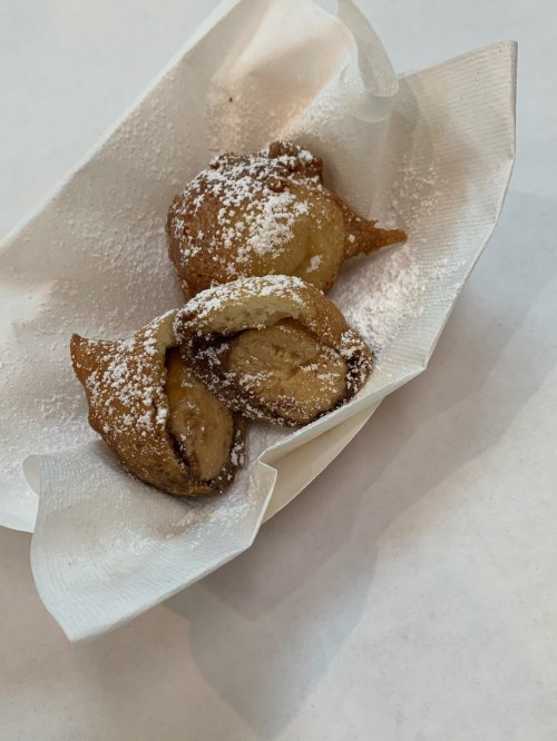 Three powdered sugar-dusted pastries on a white paper napkin.