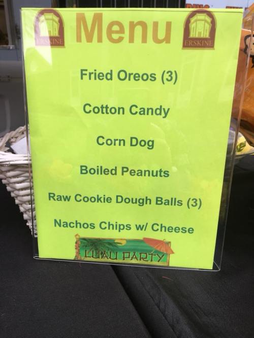 Bright yellow menu board listing snacks: Fried Oreos, Cotton Candy, Corn Dog, Boiled Peanuts, Raw Cookie Dough Balls, Nachos.
