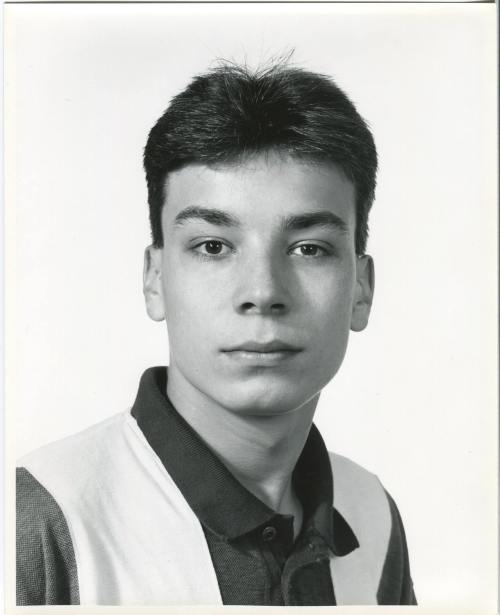 Black and white portrait of a young man with short hair, wearing a collared shirt, looking directly at the camera.