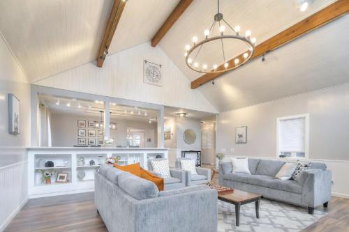 Bright living room with high ceilings, large windows, and cozy seating, featuring a chandelier and decorative shelves.