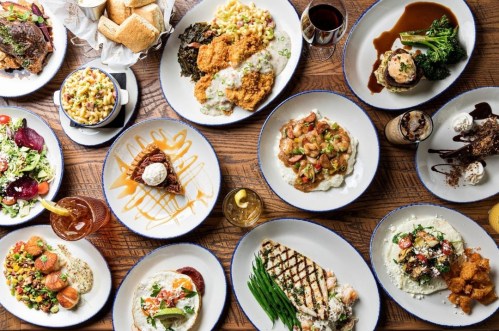 A variety of delicious dishes including seafood, pasta, salads, and desserts arranged on a wooden table.