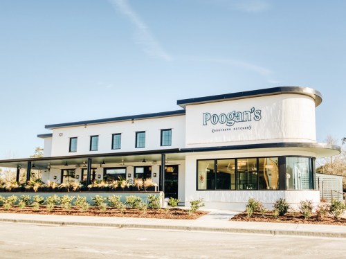 Exterior view of Poogan's restaurant, featuring a modern design and landscaped entrance on a sunny day.