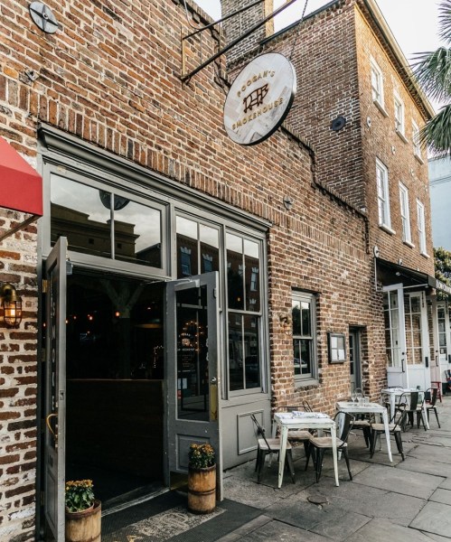 Exterior of a brick restaurant with a sign, featuring outdoor seating and a welcoming entrance.